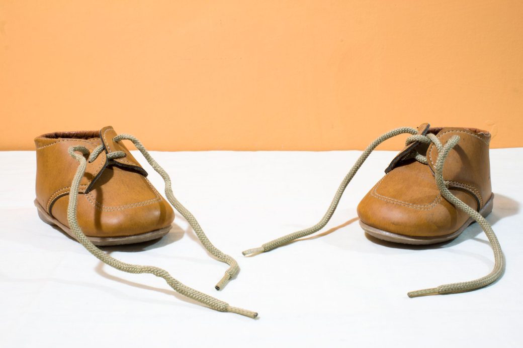 Adorable brown leather baby shoes with laces displayed on a white surface, perfect for children's fashion projects.