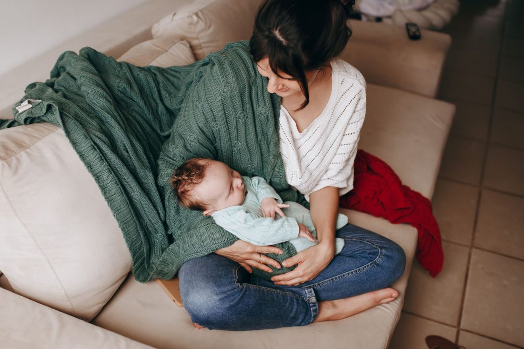 Tender moment of mother holding her baby on a cozy sofa indoors.