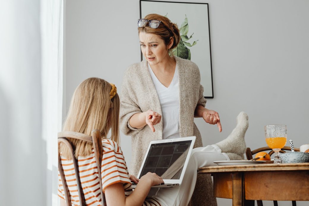 A mother scolds her daughter in a home setting, emphasizing family dynamics.