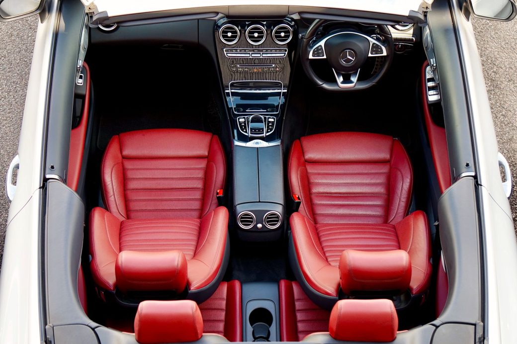 Top-down view of a luxury convertible with red leather seats and sleek dashboard controls.