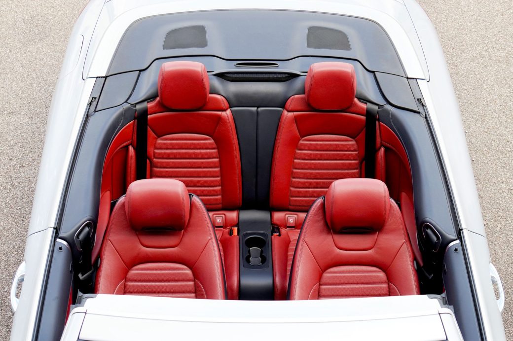 Overhead view of a luxurious convertible car with red leather seats and sleek design.