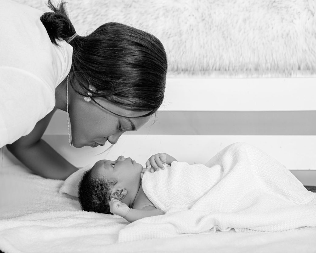 A mother lovingly gazes at her newborn baby wrapped in a soft blanket.