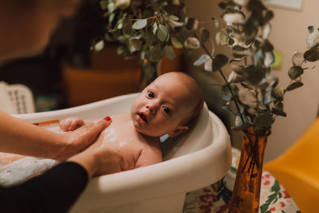 A cute baby being bathed with gentle care in a warm, cozy indoor setting with soft lighting.