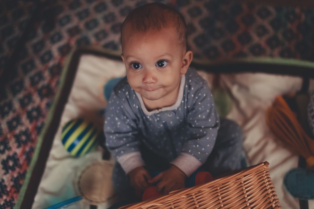 Cute baby in blue pajamas playing with colorful toys in a cozy indoor setting.