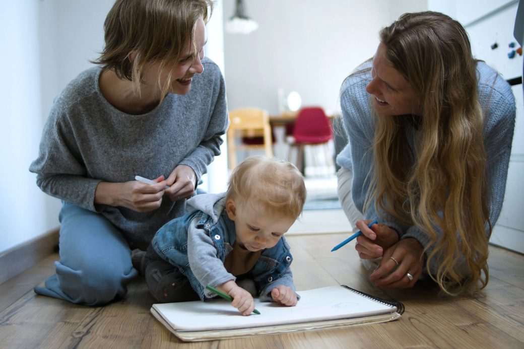 A heartwarming moment of two women and a baby drawing together indoors, symbolizing family bonding.