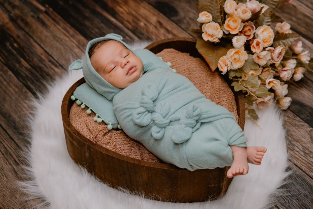 Adorable baby sleeping in a heart-shaped basket with floral decor. Perfect for baby-related projects.