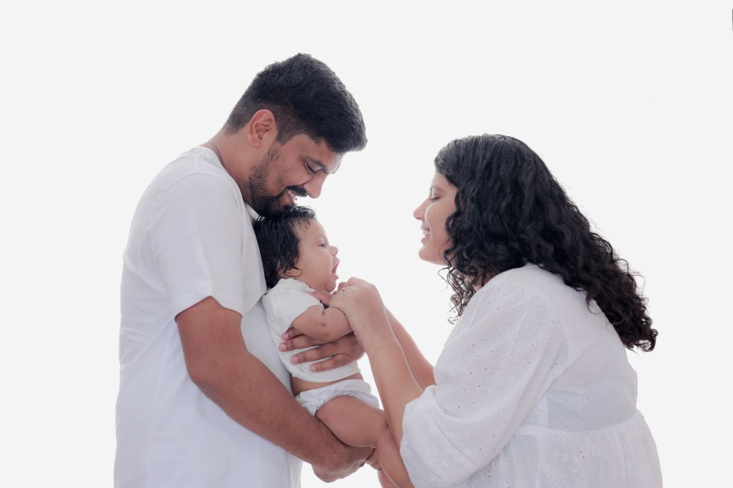 A heartfelt moment of parents smiling at their newborn baby, enjoying close family time.