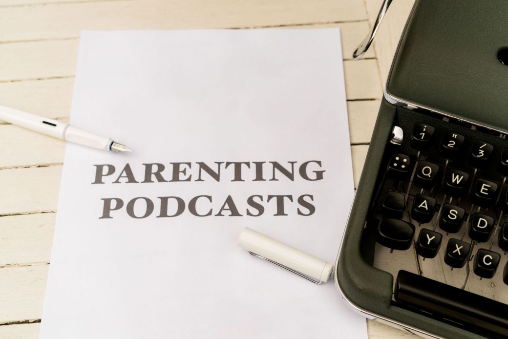 A vintage typewriter with a paper labeled 'Parenting Podcasts' on a wooden desk.