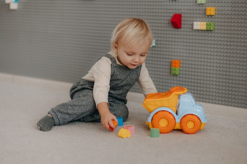 Cute toddler engaged with colorful blocks and toy truck indoors.