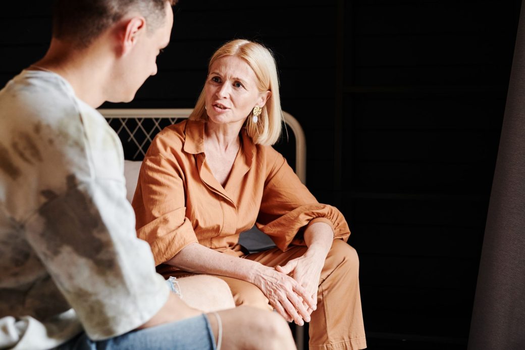 A candid moment of a mother and adult son having a heartfelt conversation indoors.