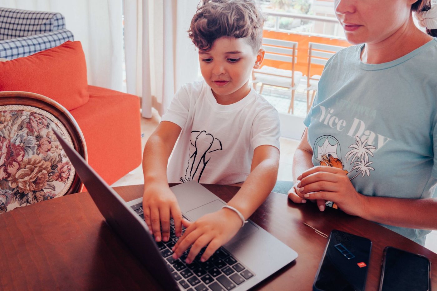 A parent and child at a home table using a laptop together.
